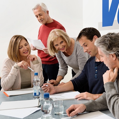 Aufbauseminare für das Vorstandsehrenamt: Fünf Personen sitzen und stehen um einen Tisch und arbeiten gemeinsam